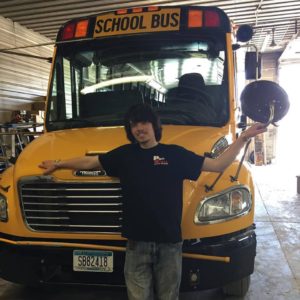 A man standing in front of a yellow school bus.