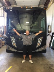 A man standing in front of a black bus.