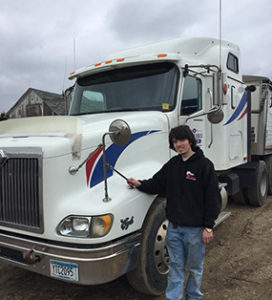 A boy standing next to a large truck.