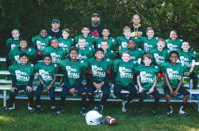 A group of young boys in green shirts and helmets.